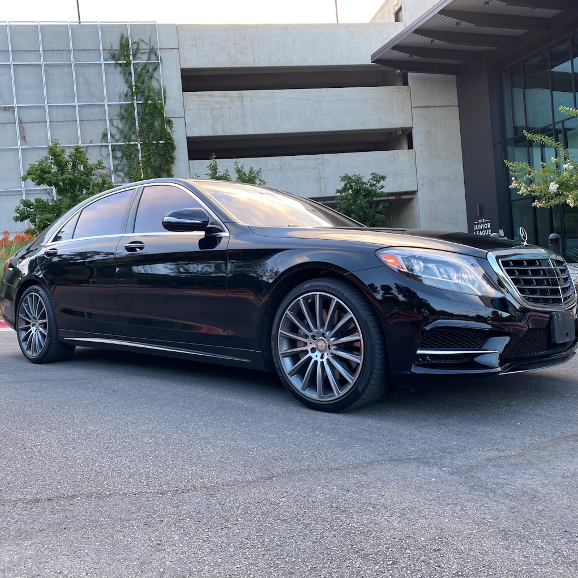 Mercedes S-Class luxury sedan providing executive transportation service in front of modern corporate office building